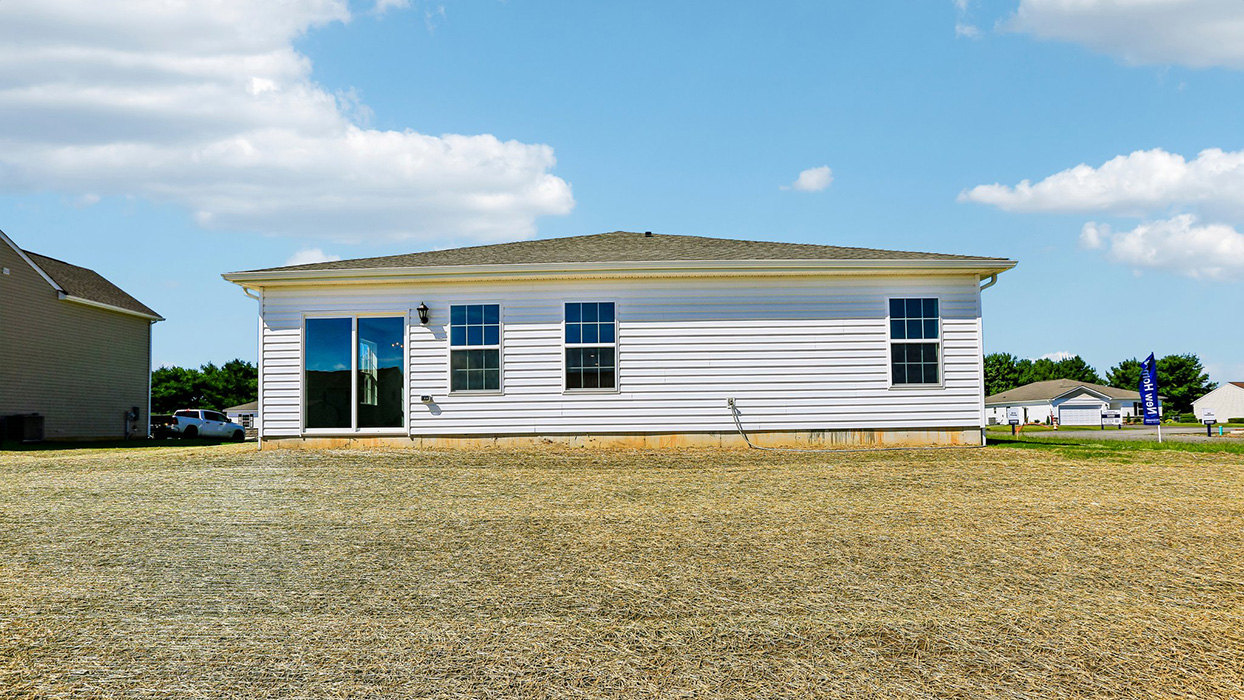 A Neuville rear exterior photo with white siding, champagne ledgestone kneewall, and a white garage door.