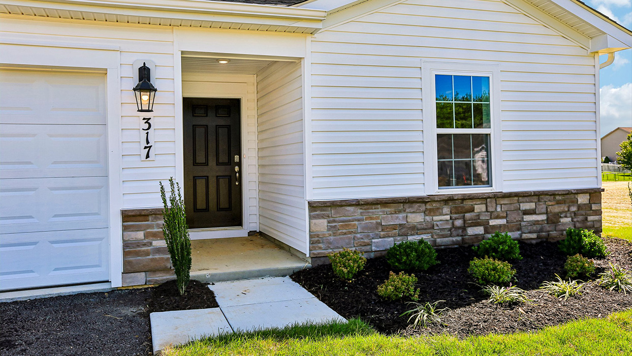 A Neuville exterior photo with white siding, champagne ledgestone kneewall, and a white garage door.