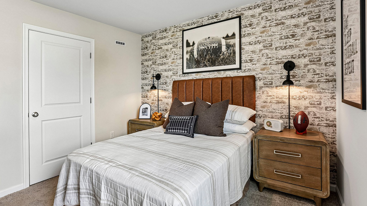 Secondary bedroom with cozy styling, accent wall design, and bedside lighting in a thoughtfully designed new home