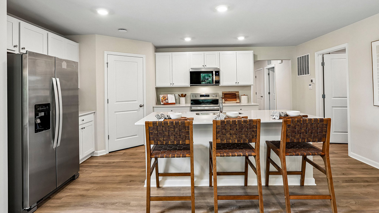 Kitchen with large island seating, white cabinetry, and stainless steel appliances