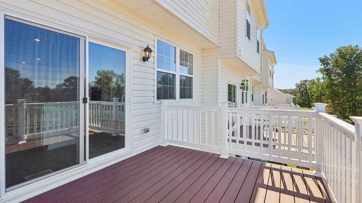 An exerior photo of the deck with white railing which is located off the kitchen area on the main level.