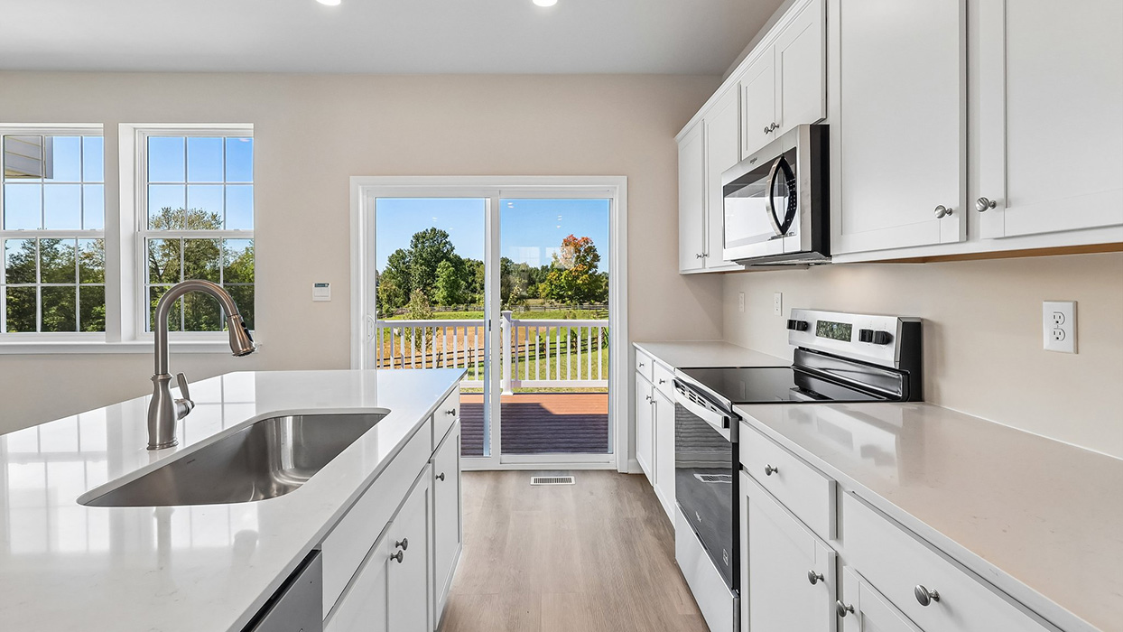 A view of the kitchen with white cabinets and stainless steel appliances.