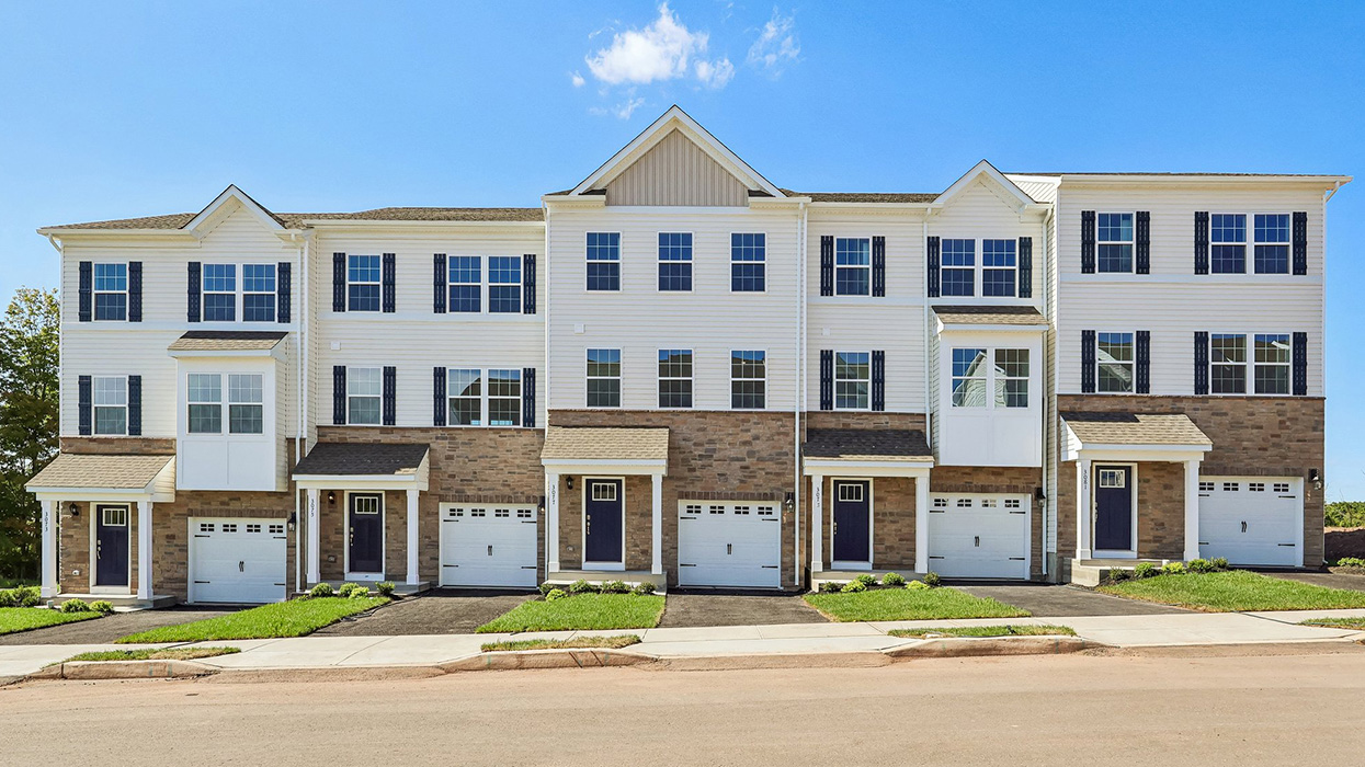 A photo of five connecting Lafayette townhomes with dakota ledgestone and white horizontal siding and a white single car garage.