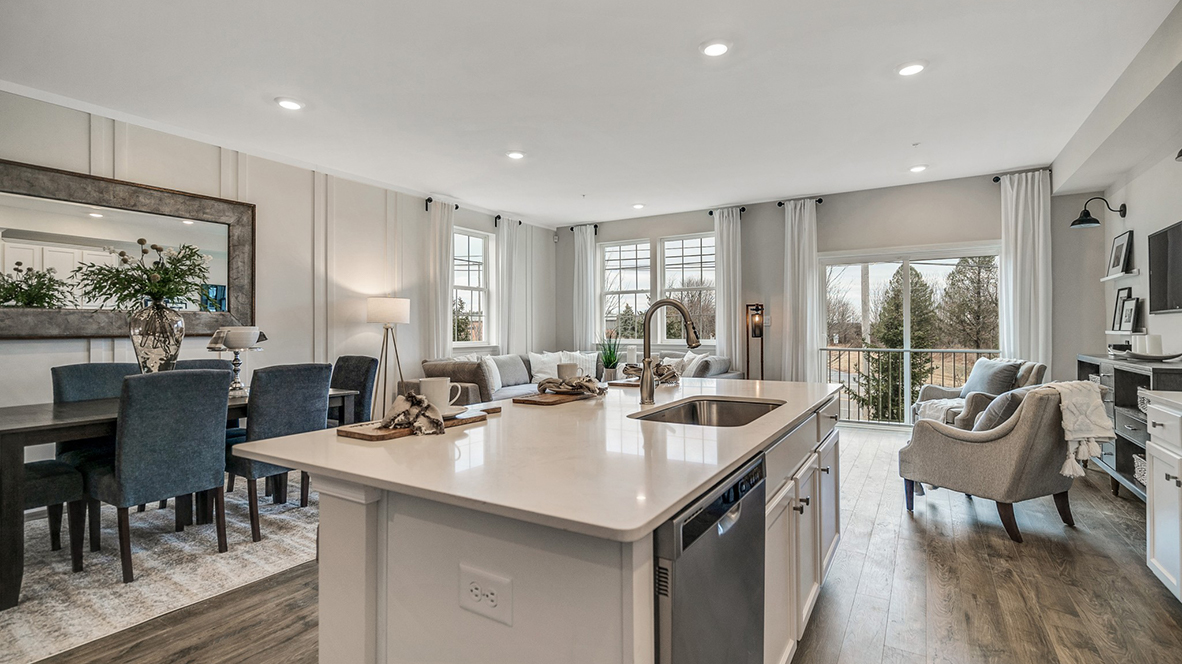 Kitchen area with large island an white counter tops and white cabinetry and stainless steel appliances. Juliet balcony door in the back left.