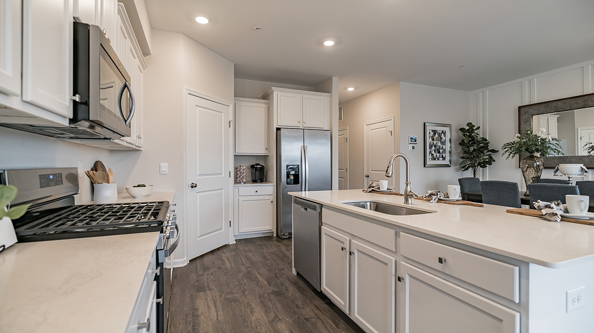 Walkway between the kitchen island and back wall with a peek into the dining area.