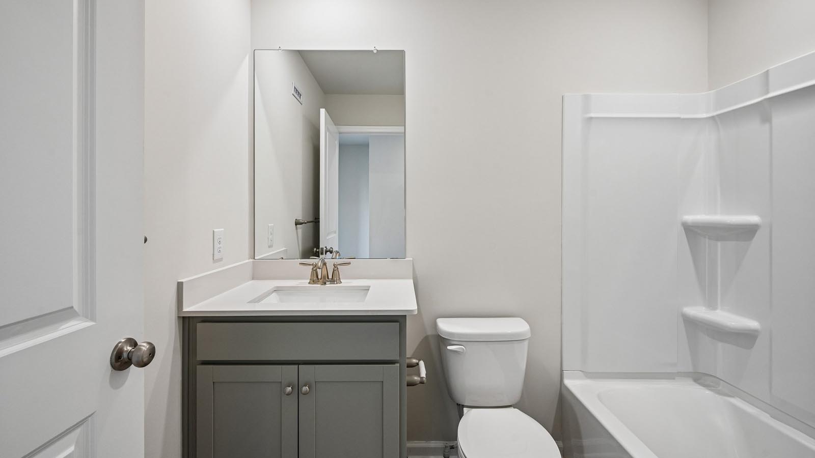 Secondary bath on the second floor with single sink vanity and shower tub.