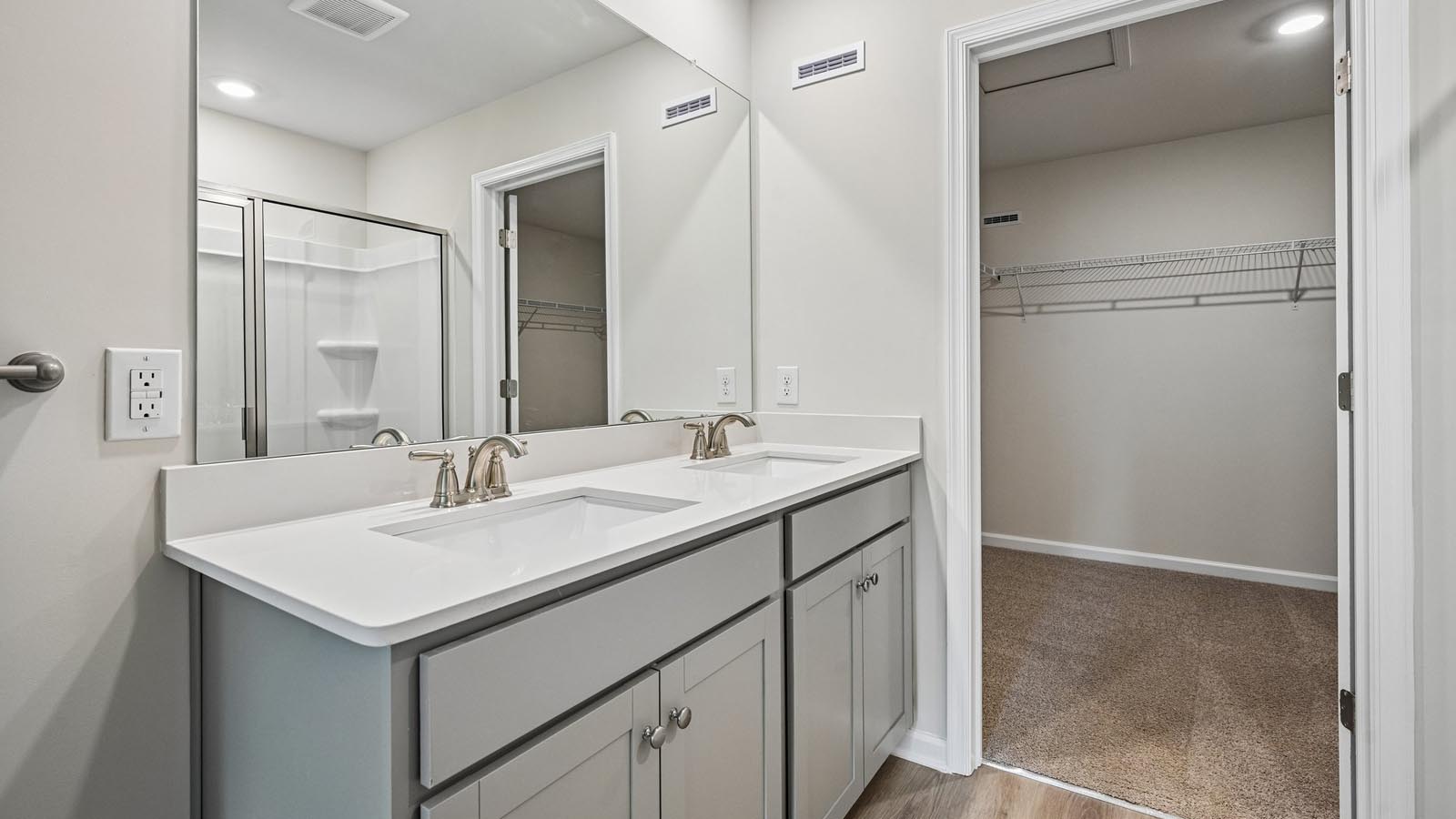 Primary bath with double sink gray vanity and white shower with connecting closet.