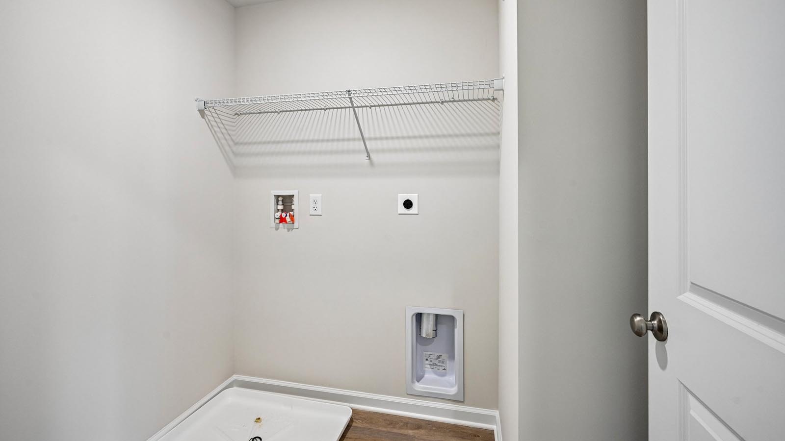 Laundry room with hookups for your washer and dryer with a shelf above.