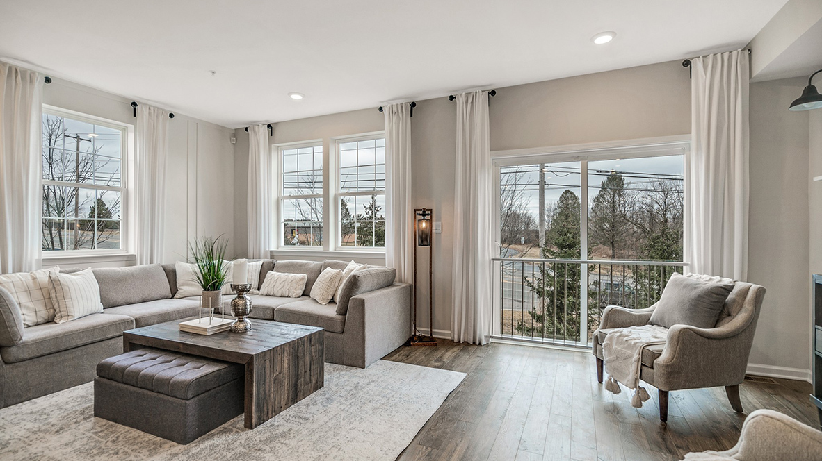 Living area with a single window on the back left wall and a double windows and back Juliet glass balcony door on the back wall.