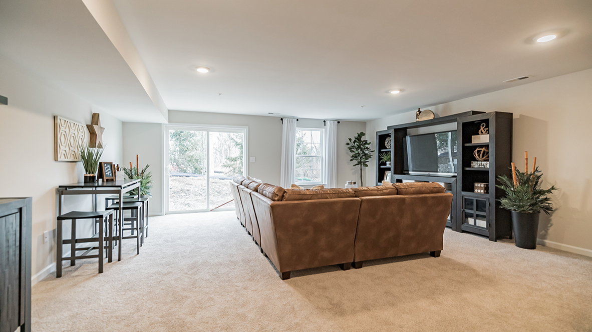 Different view of the recreation room of the finished basement with the back sliding glass door to the backyard.