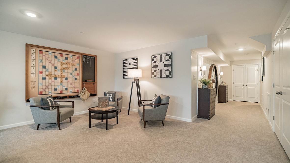 Different view of the recreation room with view into hallway next to the stairs.