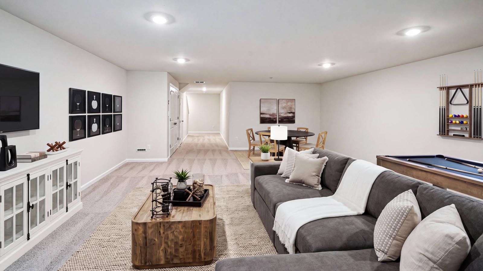 Different view of the recreation room with view into hallway next to the stairs.