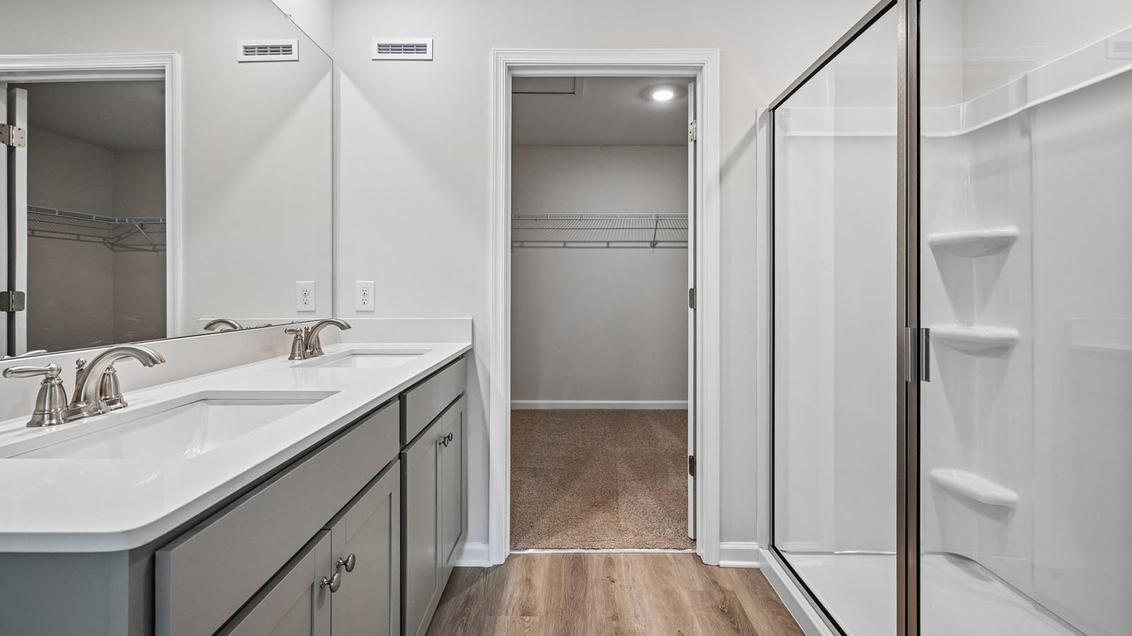 Primary bath with double sink gray vanity and white shower with connecting closet.