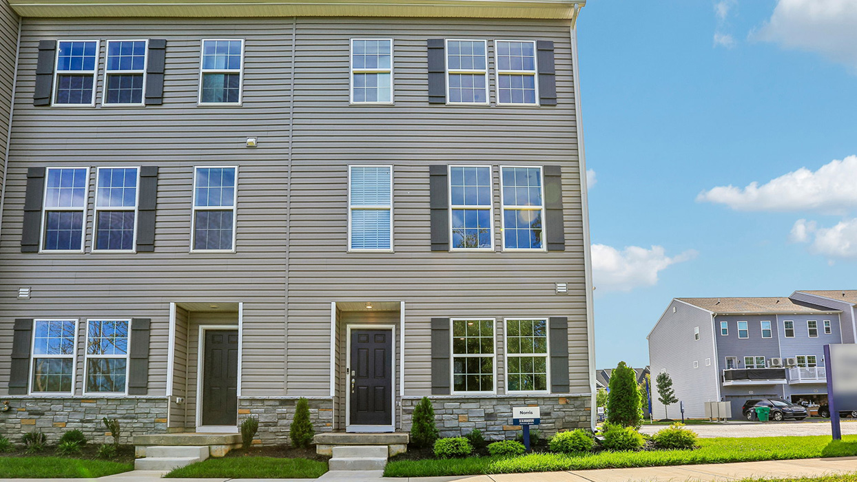 a photo of the norris plan 6-unit townhome building with slate gray color siding dark gray shutters and a navy front door
