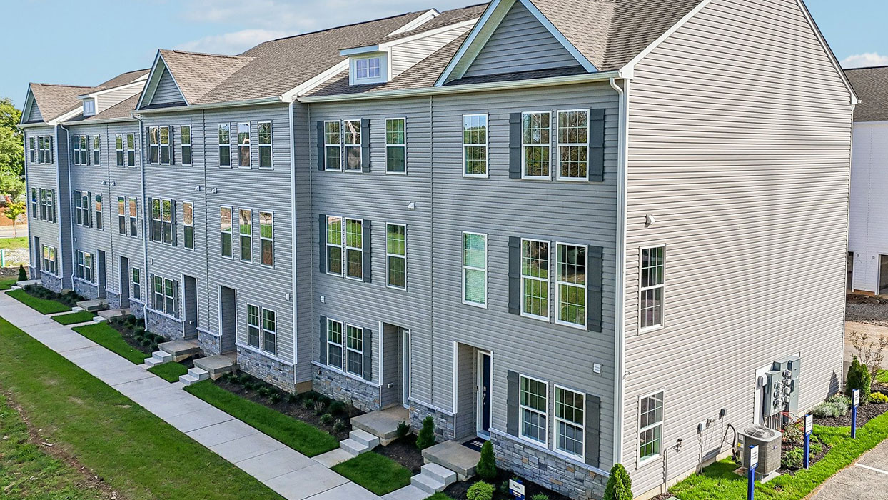 a photo of the norris plan 6-unit townhome building with slate gray color siding dark gray shutters and a navy front door