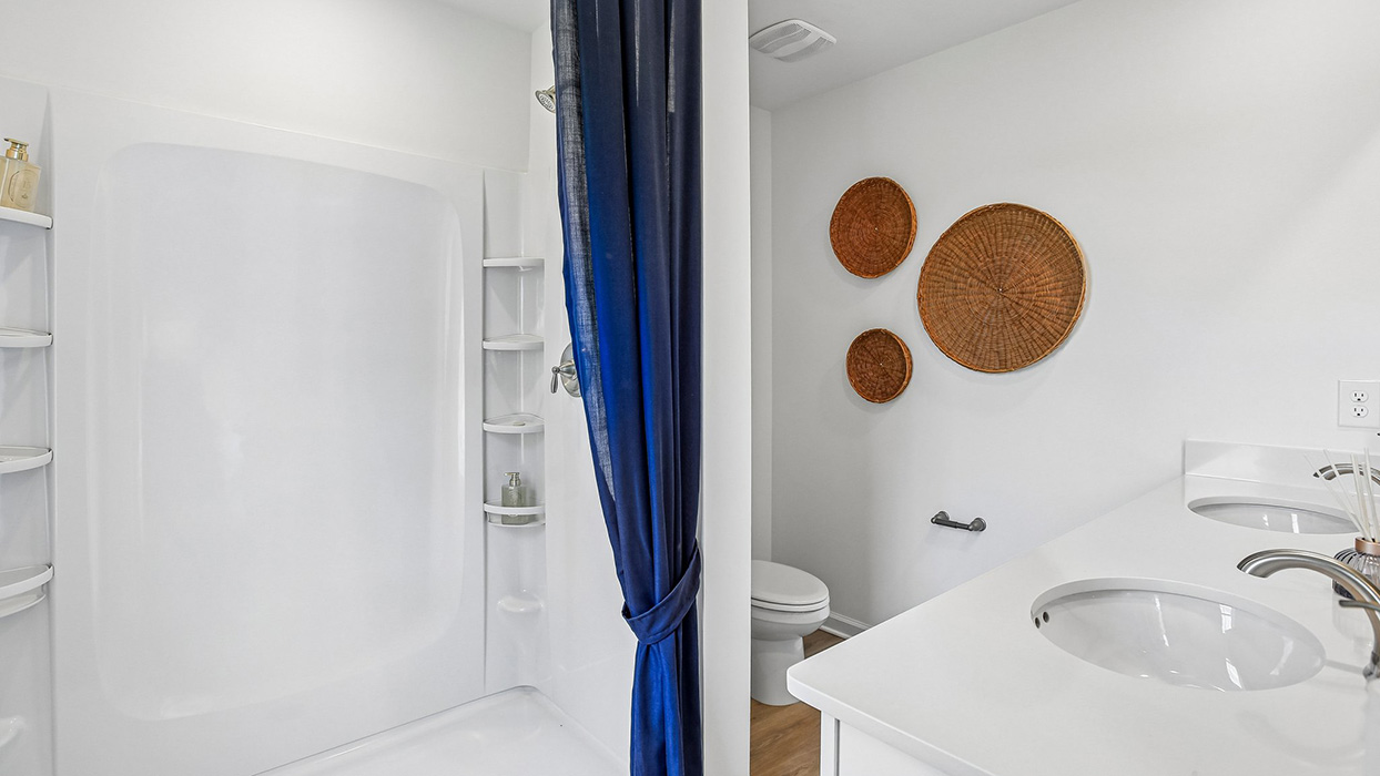 Primary bathroom with double bowl vanity, shower and toilet across
