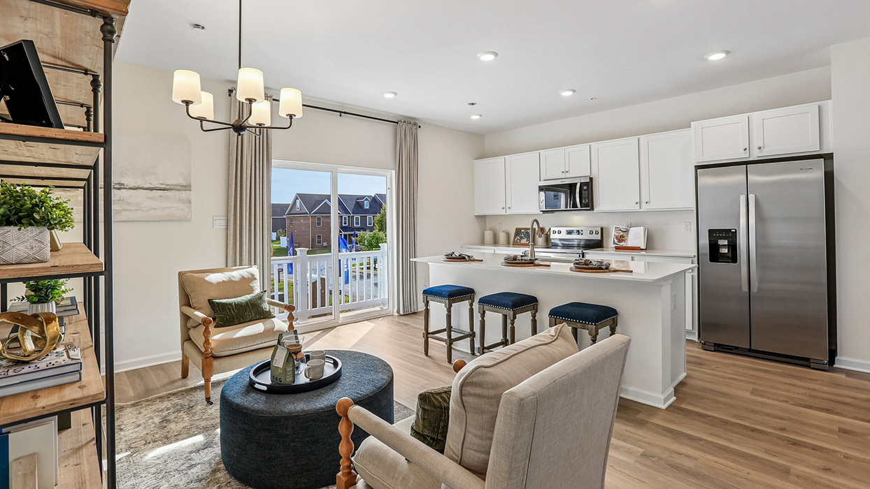 Bright living and kitchen area with large island with white counter tops and white cabinetry