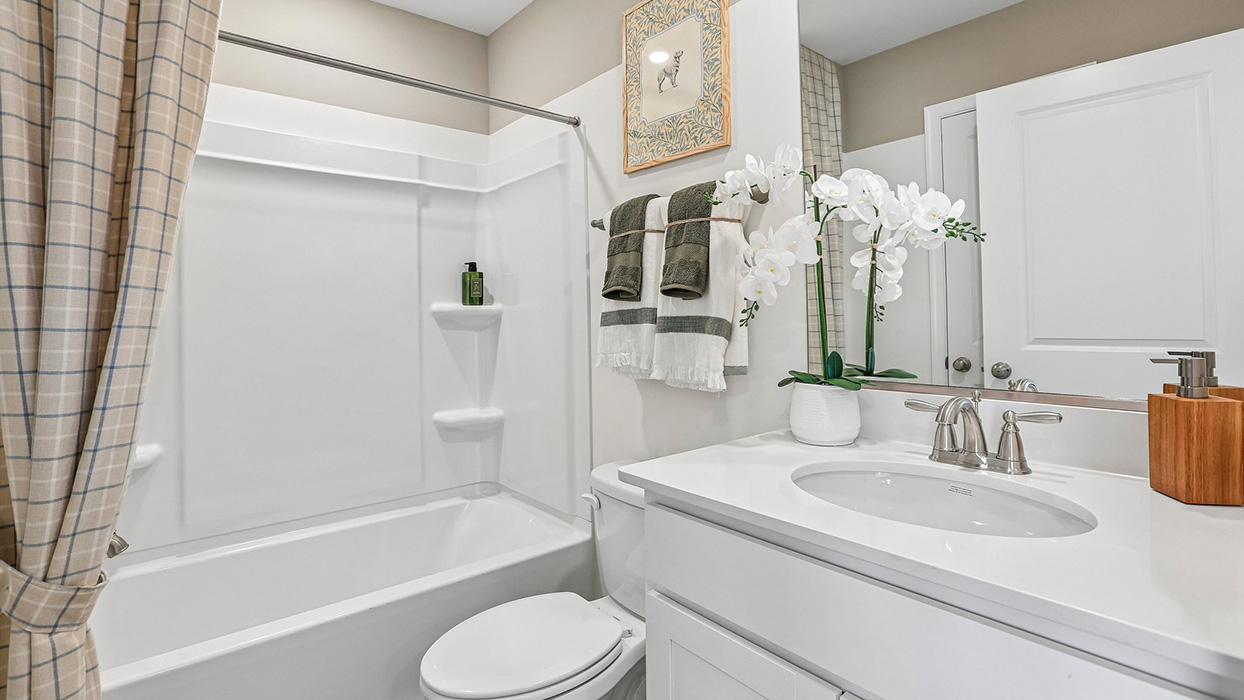 Secondary bathroom with single sink white vanity and tub shower