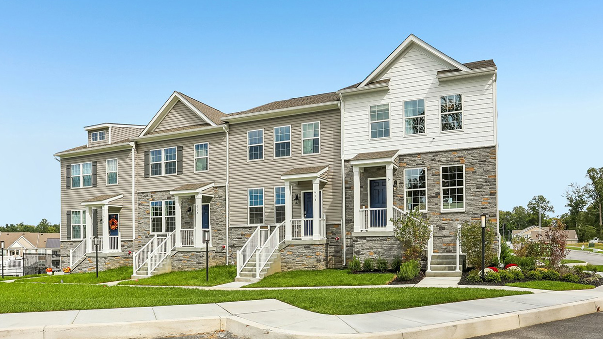 A photo of the Norris 3 story townhome model unit with partial stone wallwhite siding and staircase leading up the front door