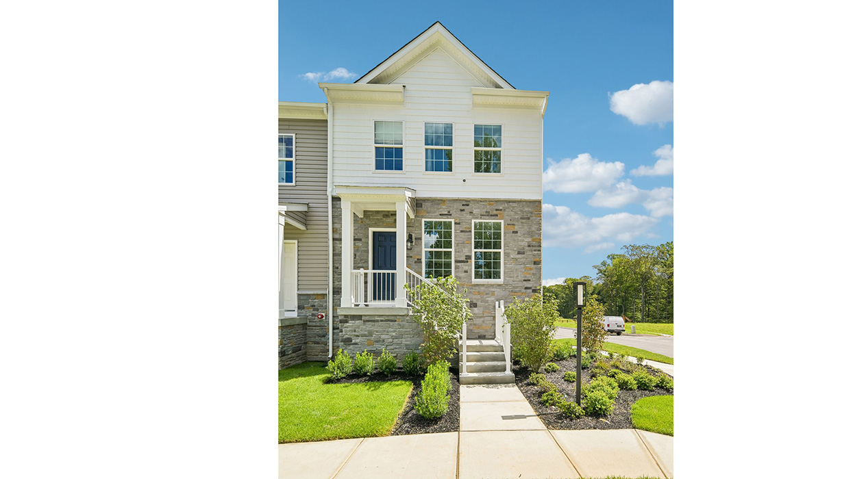 A photo of the Norris 3 story townhome model unit with partial stone wallwhite siding and staircase leading up the front door