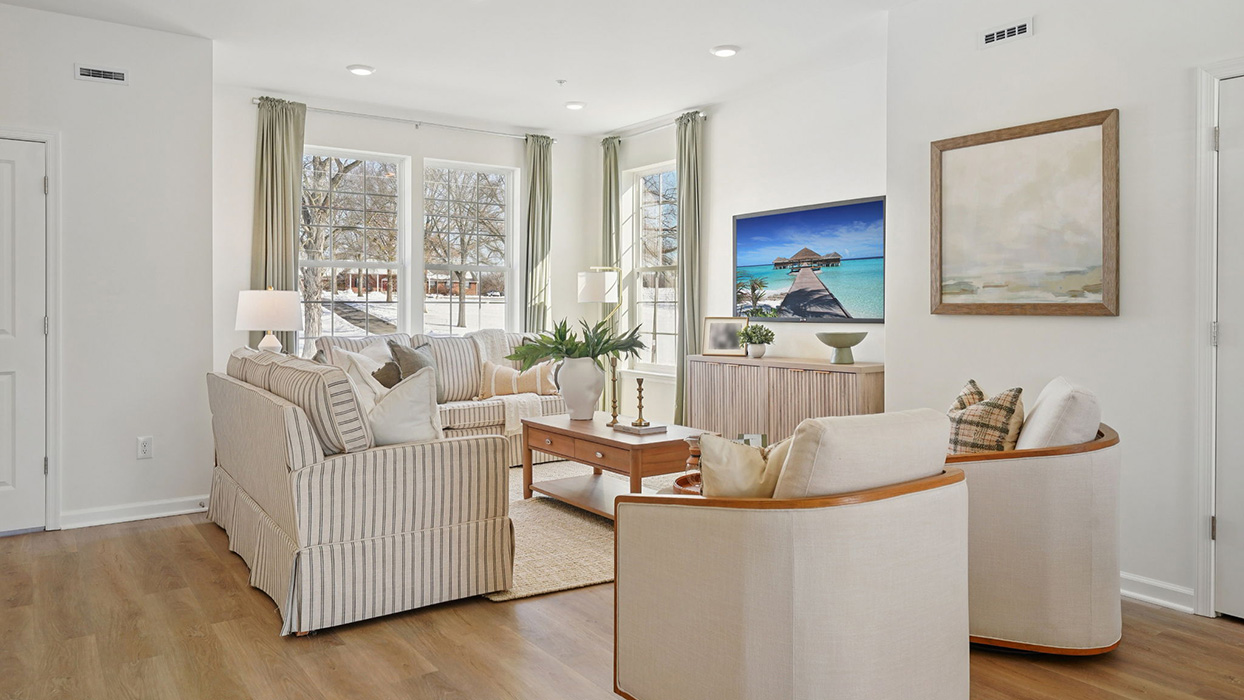Spacious living room with sofa seating arrangement, TV console, and large windows bringing in abundant natural light
