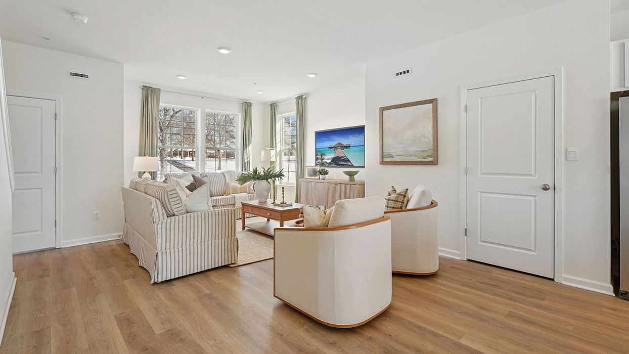 Living room with upholstered seating, wood flooring, and wall art, offering a clean and open layout