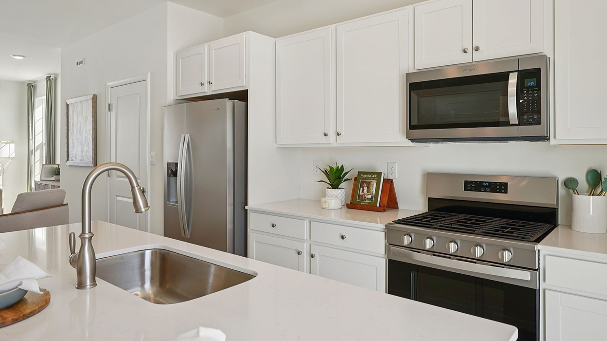Bright kitchen with stainless steel appliances, white cabinetry, and island sink in the foreground with modern finishes
