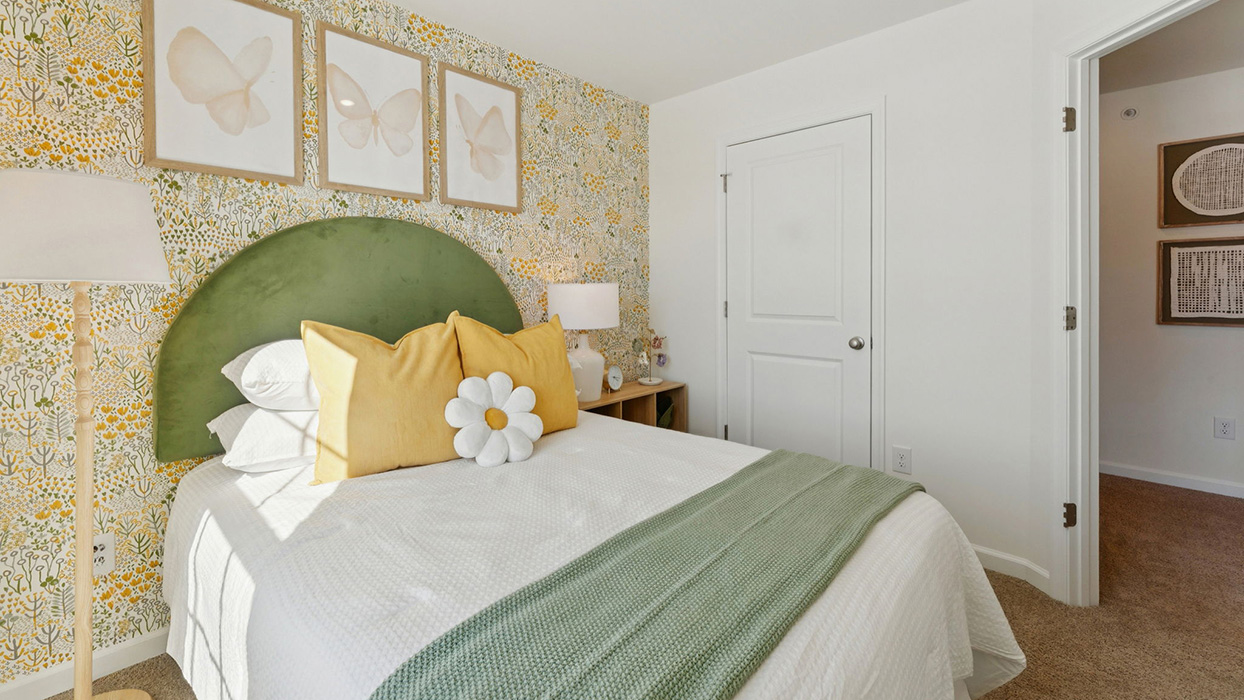 Secondary bedroom with decorative accent wall, upholstered bed, and hallway view