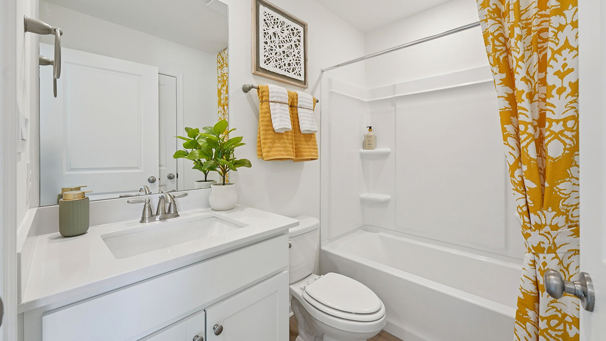 Secondary bathroom with single sink vanity, tub shower, and bright white finishes