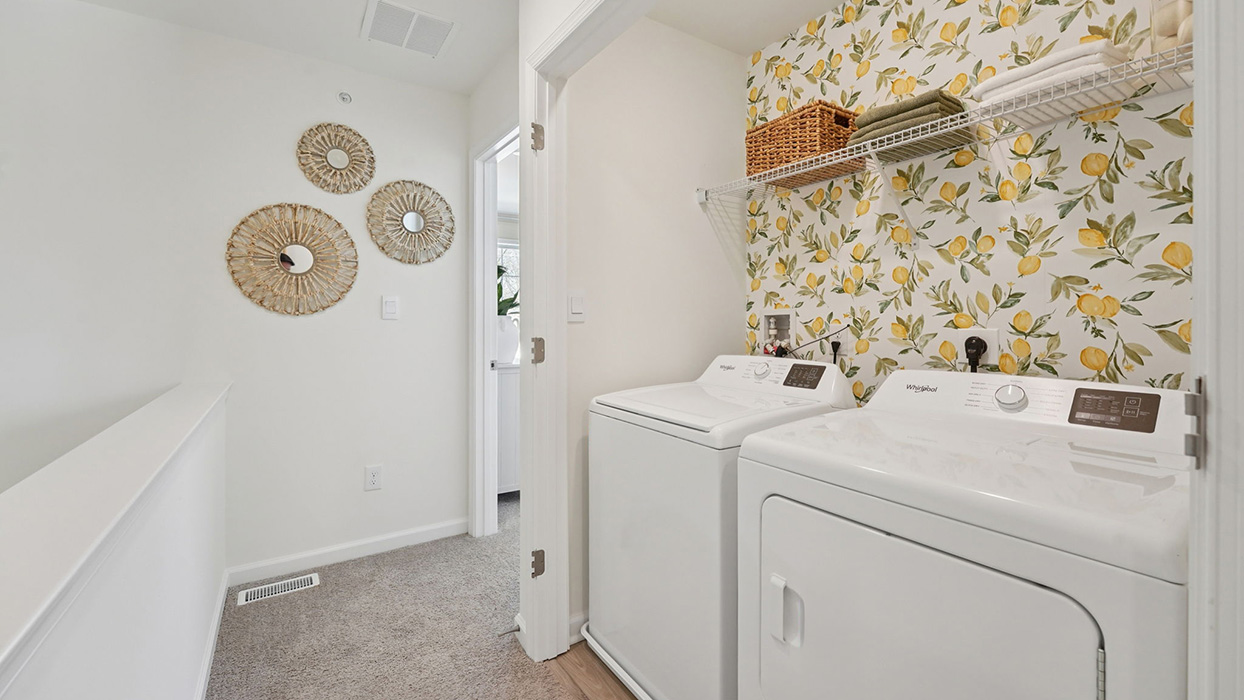 Laundry area with washer and dryer, open shelving, and decorative accent wall