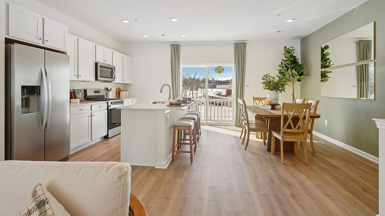 Open-concept kitchen and dining area with island seating, stainless steel appliances, and large sliding glass door for natural light