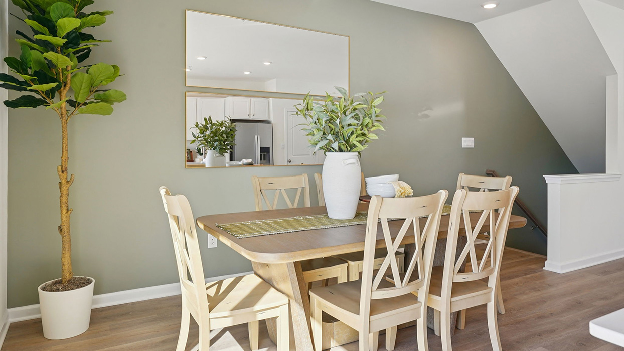 Bright dining area with six-seat table, decorative wall mirror, and large windowed sliding door to outdoor space