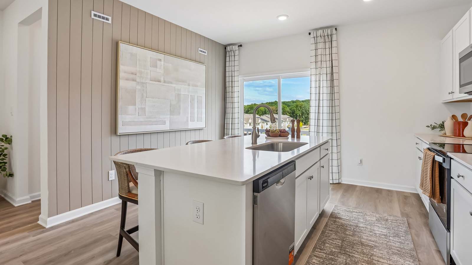 Bright spacious kitchen area with large island with white counter tops and white cabinetry and stainless steel appliances