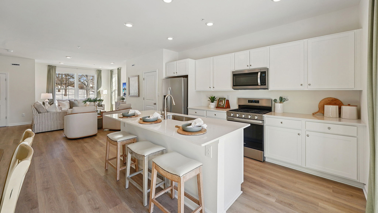 Kitchen area with large island, white counter tops, and white cabinetry and stainless steel appliances