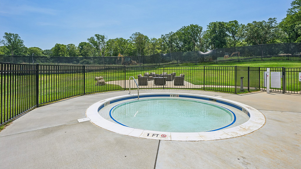 Poolside wading area with shallow circular design, safety markings, and fenced seating area beyond