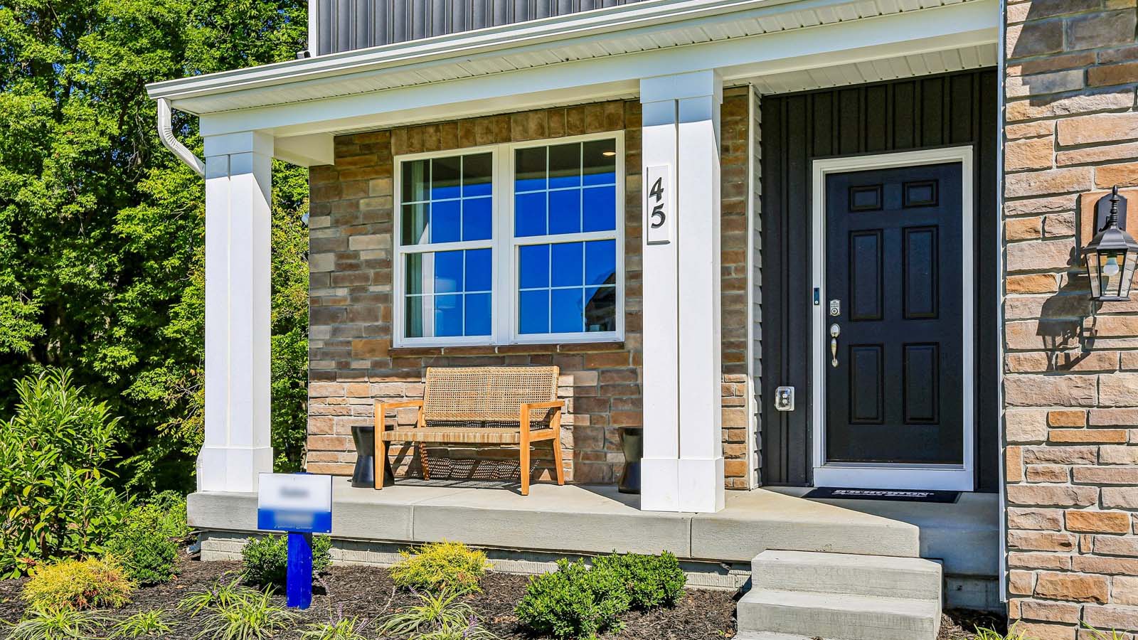 The front porch of a two-story Galen home with tricorn black front door.