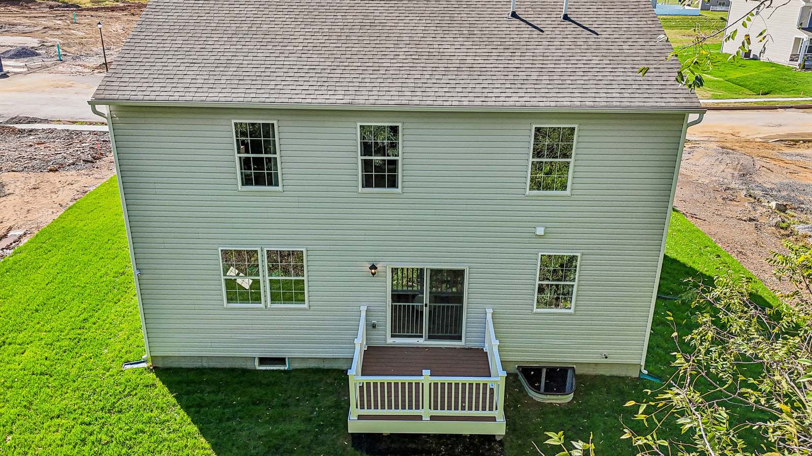 An aerial front view of a two-story Galen home featuring covered porch, ironstone board and batten siding, stone accents, and stone siding surrounding a white two car garage in Bennington.