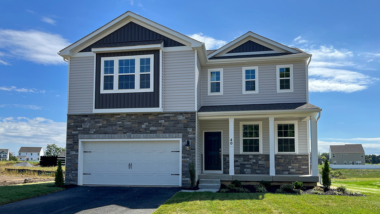 A two-story Galen home with wicker siding, midnight surf board and batten accent siding, and champagne ledgestone surrounding a white two car garage.