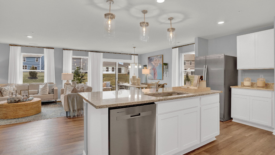 Open-concept living area with spacious kitchen island, pendant lighting, and seamless flow into the living room