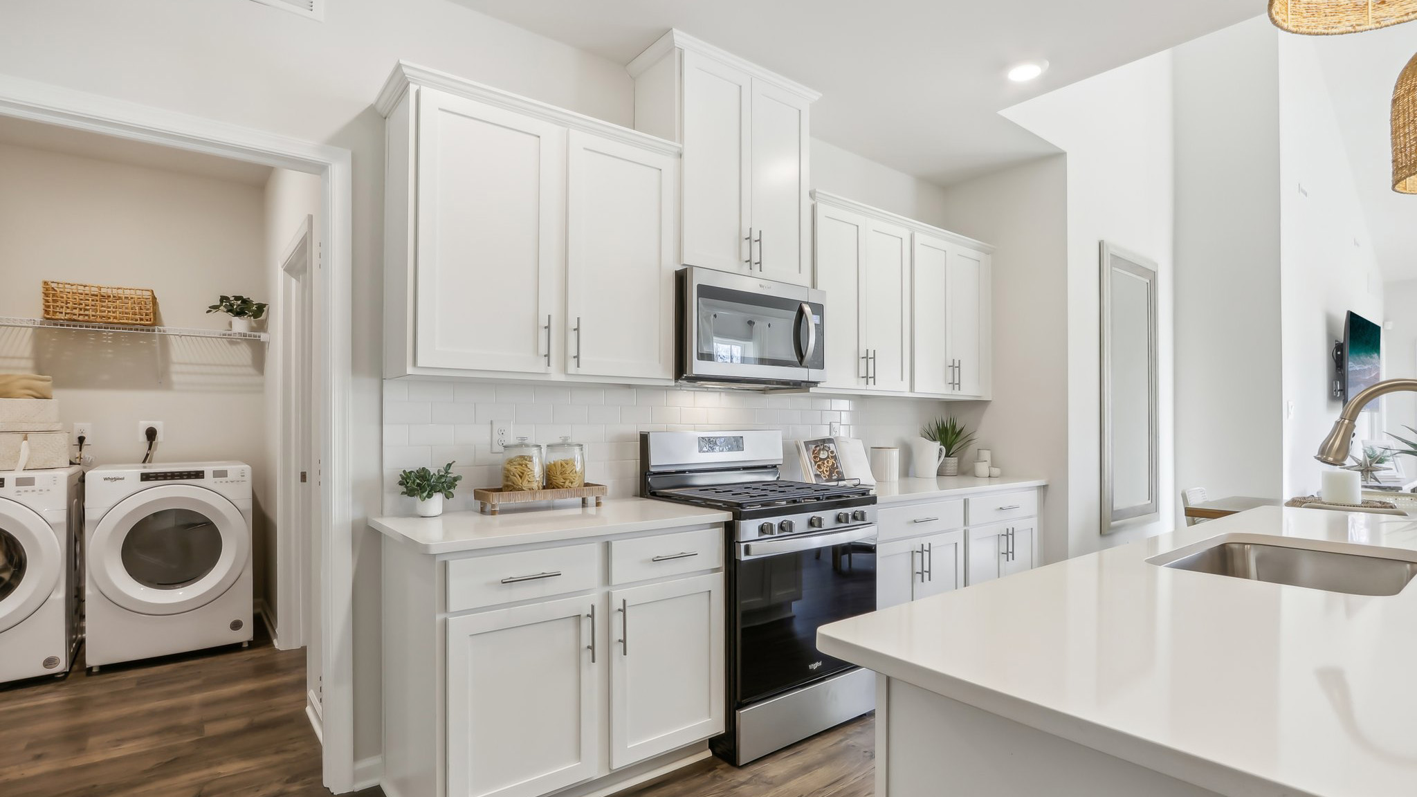 white kitchen with white island and stainless-steel appliances and silver