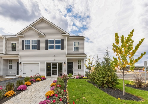 Exterior front image of the model townhome with white horizontal paneling with a white single car garage.