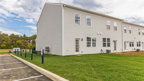 Exterior side and back image of the model townhome with white horizontal paneling with a back door entrance.