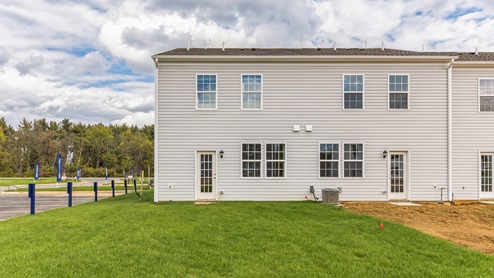 Exterior back image of the model townhome with white horizontal paneling with a back door entrance.