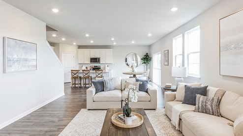 Different view of the living area standing in front of where a tv could go, overseeing the kitchen and dining area in the back of the image.