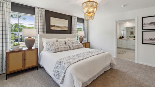Primary bedroom has two large single windows on either side of the bed and a connecting large full bath with two double sink white vanities.