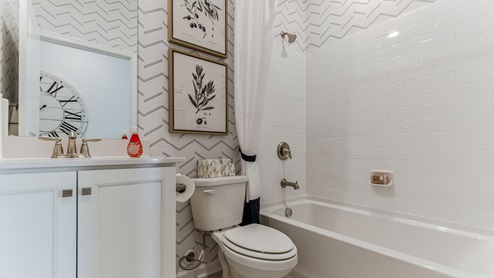 Full bath with a white single sink vanity next to the entryway storage nook.