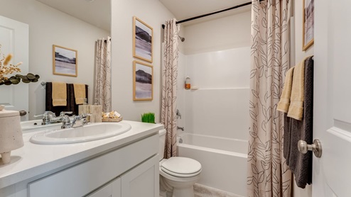 bathroom with white cabinet, white toilet, and combination shower / tub
