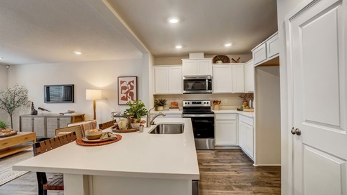 kitchen with a pantry, island, stainless steel appliances, quartz countertops, eat bar, and white shaker-style cabinets
