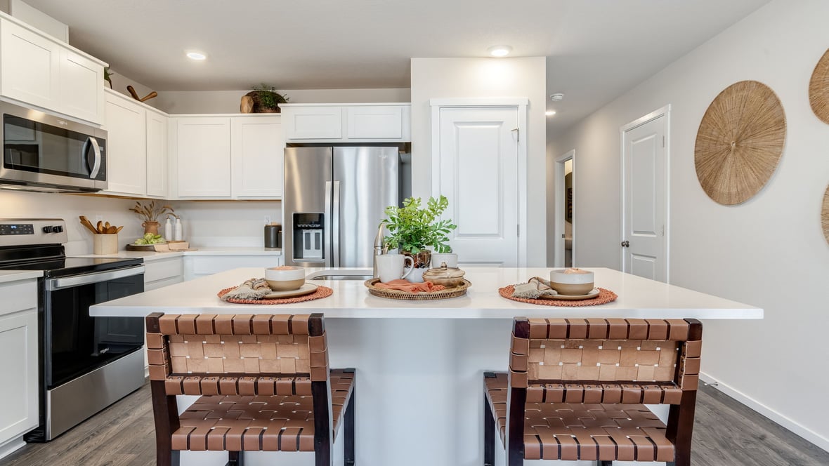 Kitchen with shaker cabinets, quartz counters, stainless steel appliances, pantry, and an island with a breakfast bar