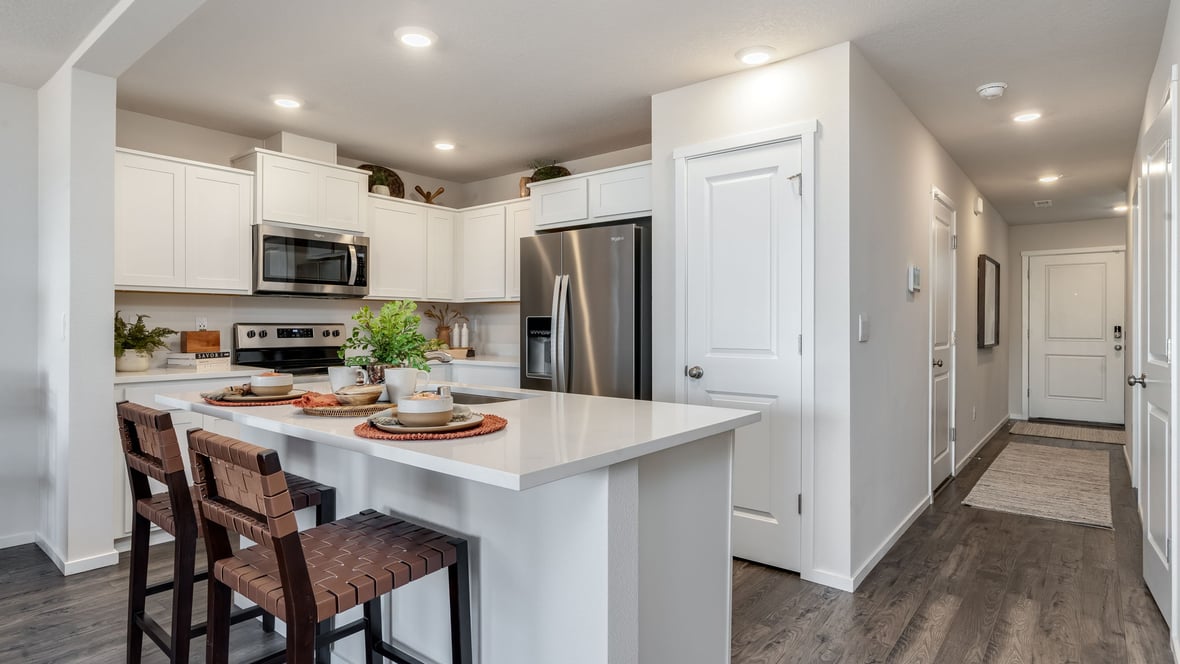 Kitchen with shaker cabinets, quartz counters, stainless steel appliances, pantry, and an island with a breakfast bar